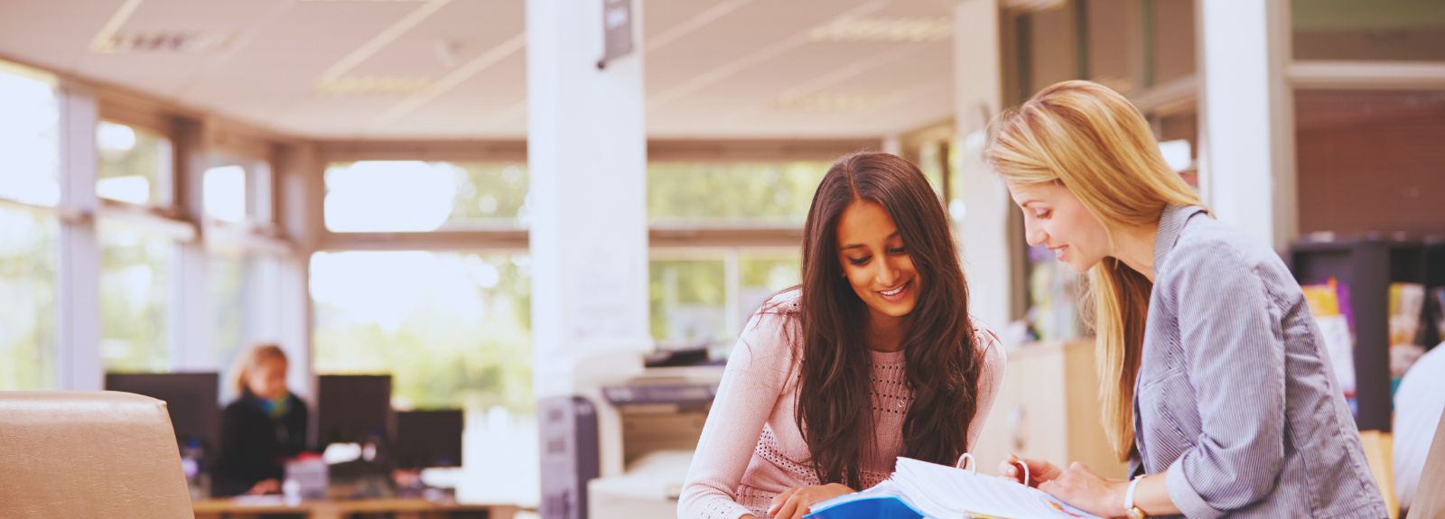 two females sitting chatting looking at a book